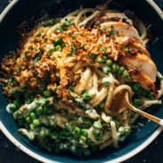 Bucatini pasta in a bowl with a fork and peas