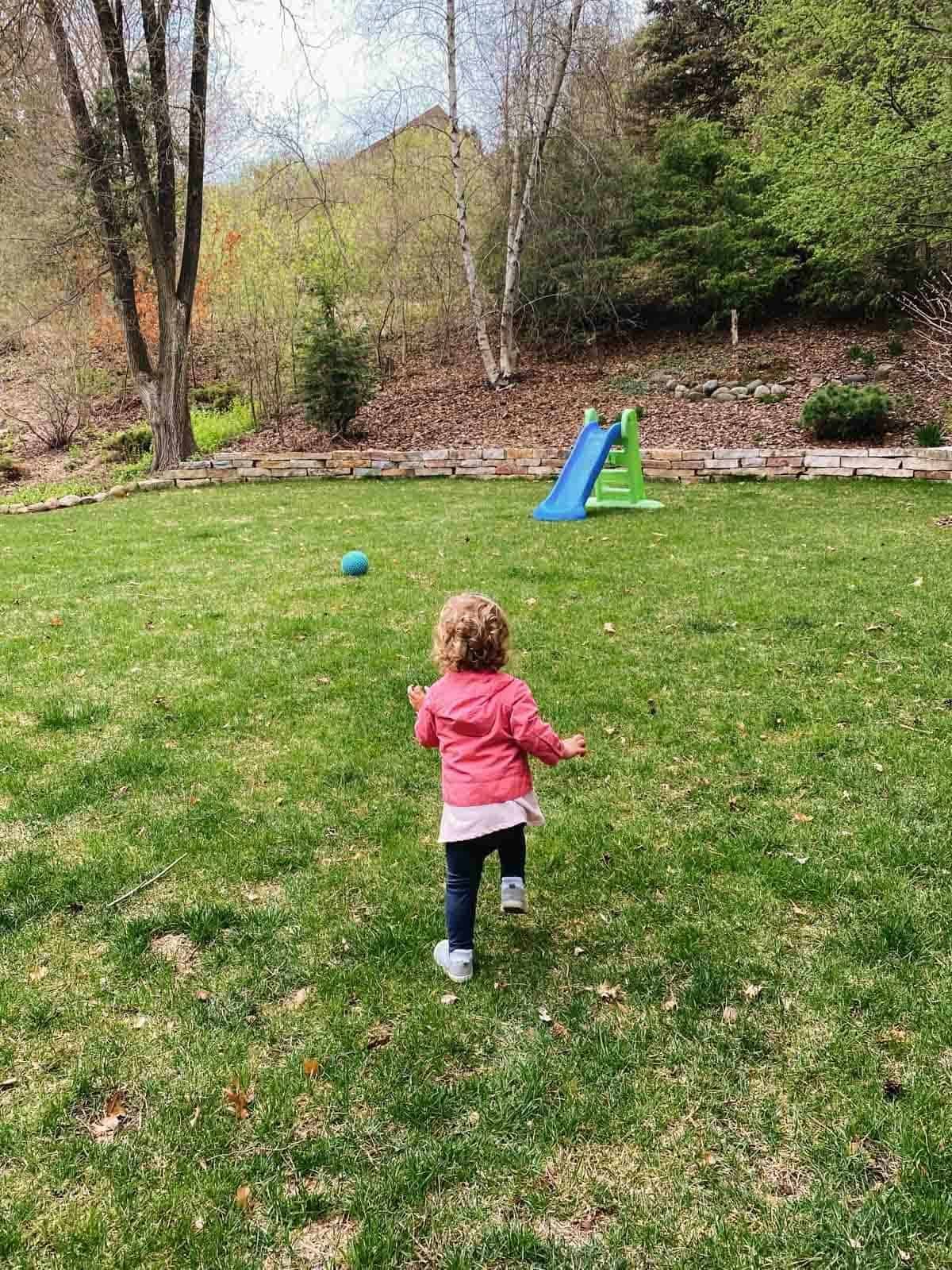 A child running to a slide in the backyard.