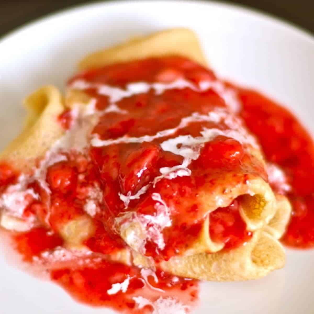 Strawberry blintzes stuffed with creamy ricotta cheese and topped with fresh sweet strawberries.