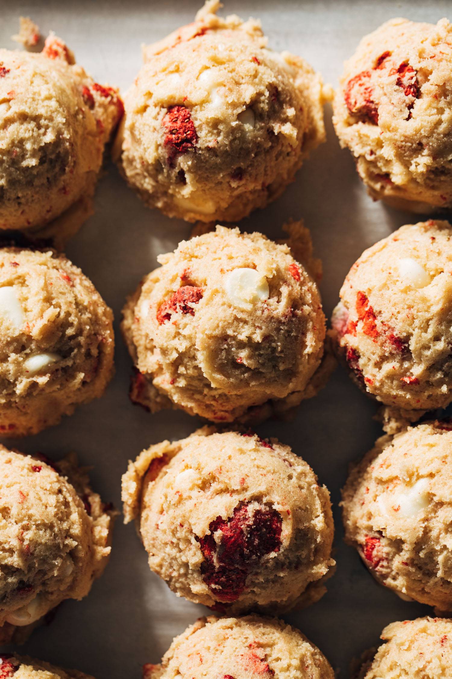 Strawberry white chocolate cookie dough rolled into balls on a sheet pan
