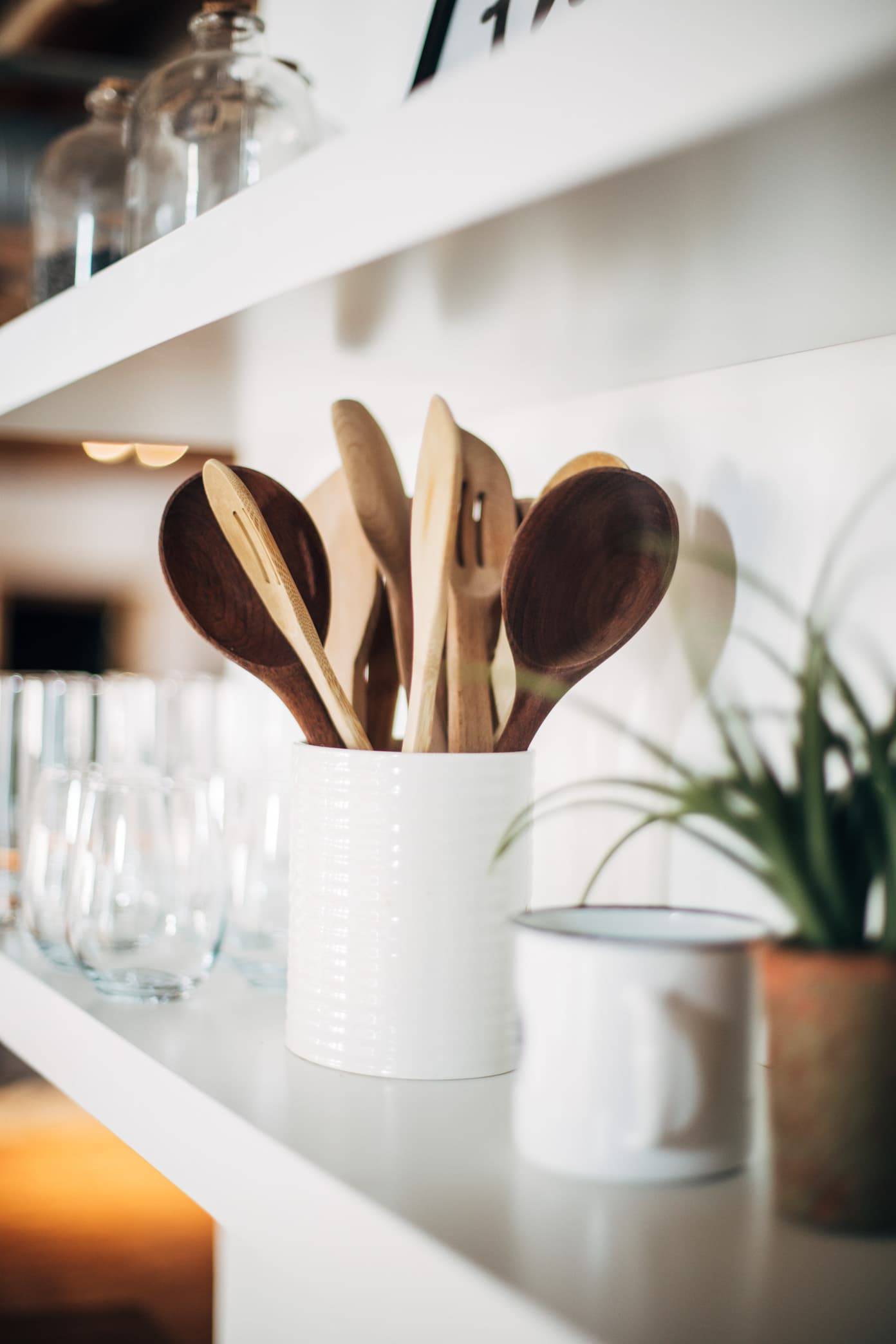Wooden spoons and kitchen items on a white shelf.