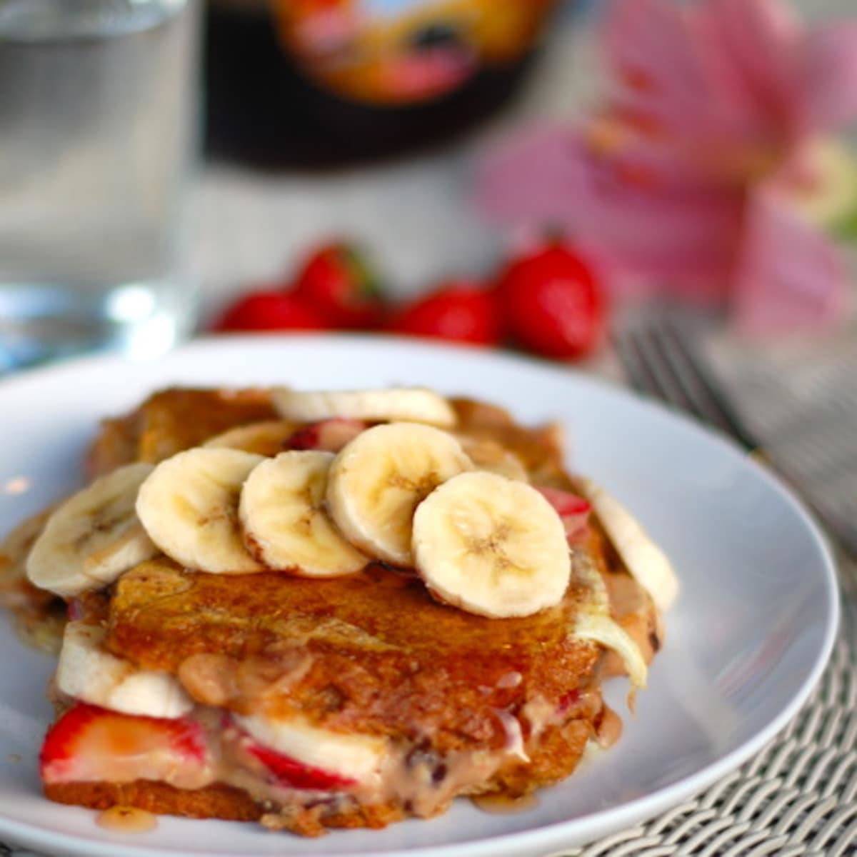 Stuffed French Toast with strawberries, bananas, and maple syrup on a plate.