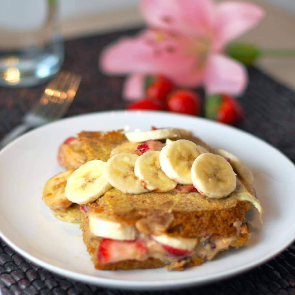 Stuffed French Toast with strawberries, bananas, and maple syrup on a plate.