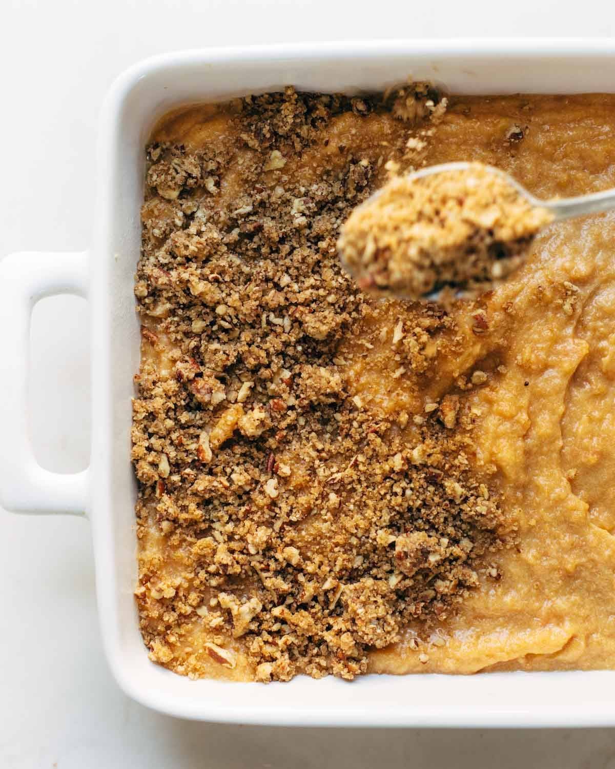 Sweet Potato Casserole with a crunchy brown sugar topping in a dish with a spoon