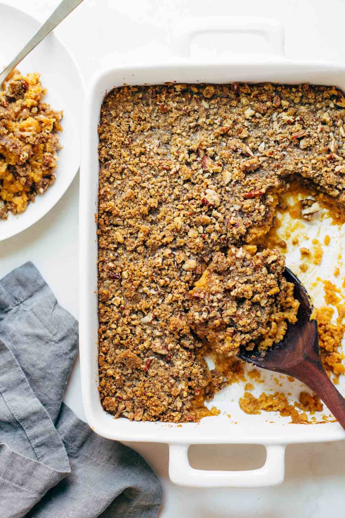 Sweet Potato Casserole with a crunchy brown sugar topping with a wooden spoon