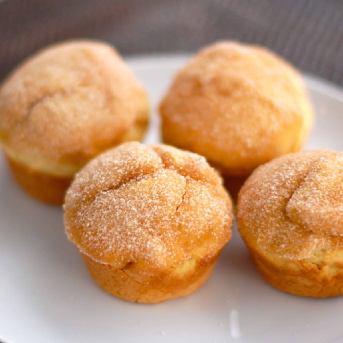 Sugar-dusted sweet potato muffins on a white plate.