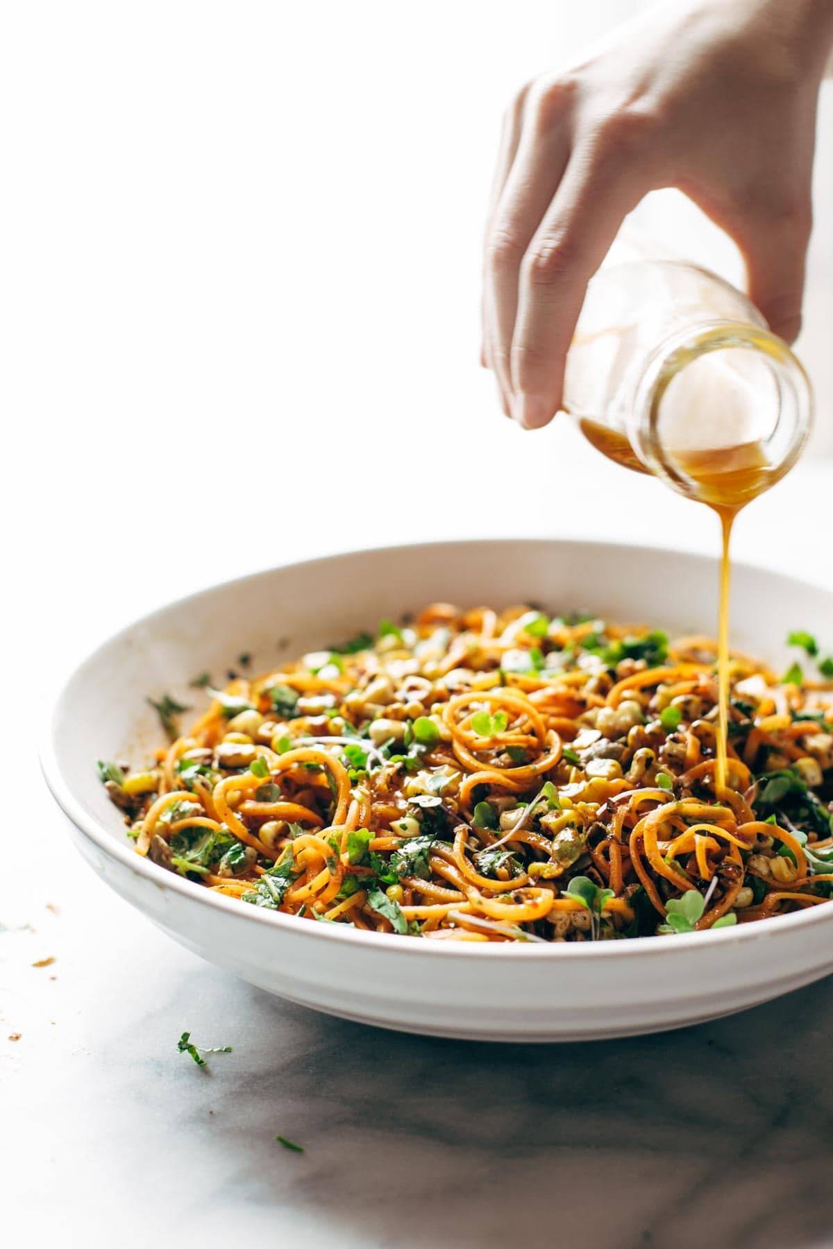 Sweet potato noodle salad in a bowl drizzled with sauce.