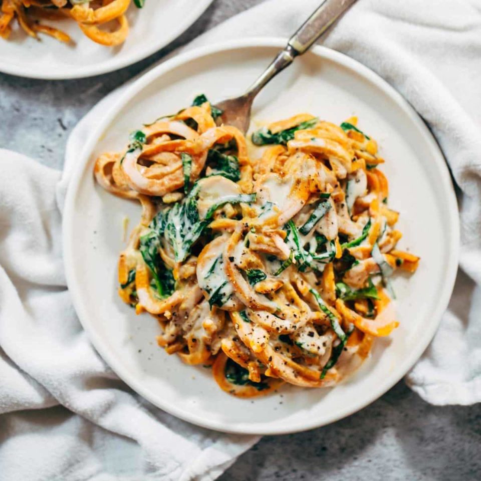 Creamy Spinach and Sweet Potato Noodles on a plate with a fork.