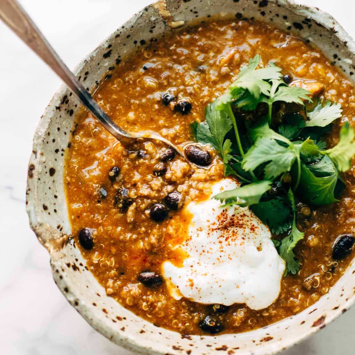 Turkey Chili and black beans with sweet potato and coriander garnished, with a spoon in a bowl.