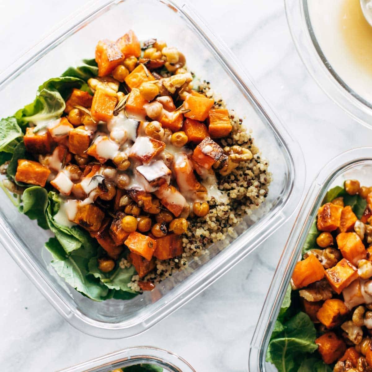 Sweet potato on a bed of greens and quinoa in a rectangular glass salad bowl.