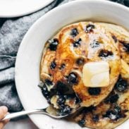 Blueberry pancakes on a plate with syrup and butter.