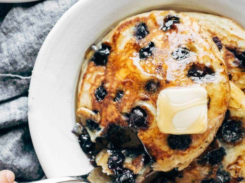 Blueberry pancakes on a plate with syrup and butter.