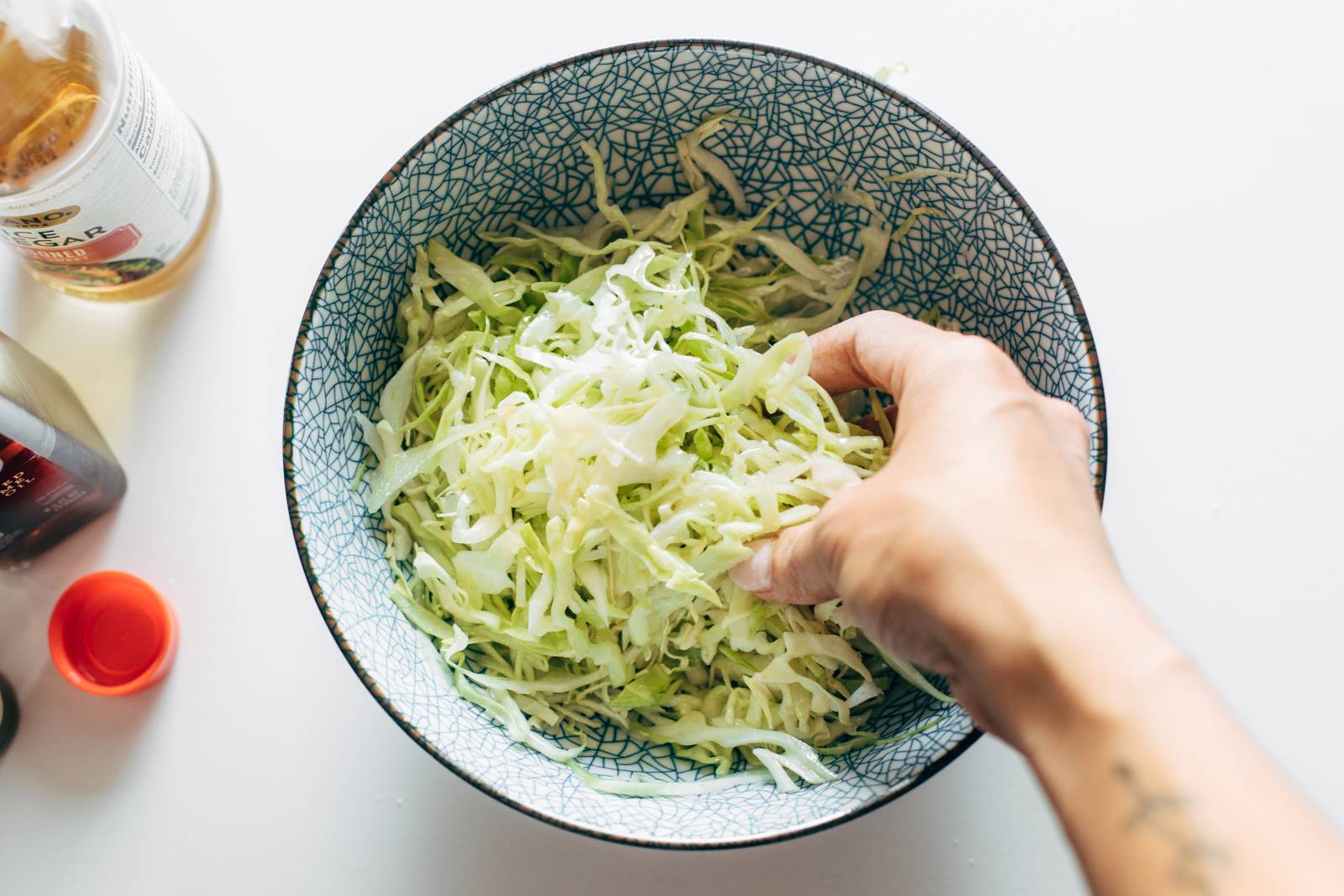 Mixing shredded coleslaw with hands.