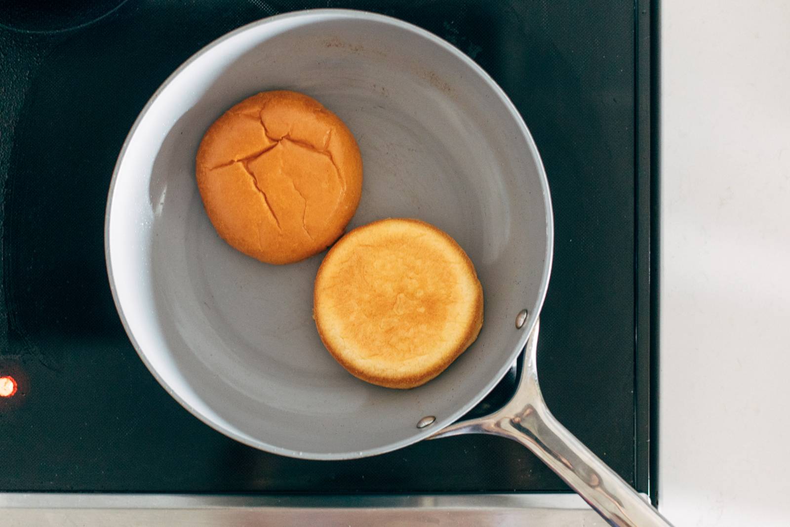 Toasting brioche buns in a pan on the stove.