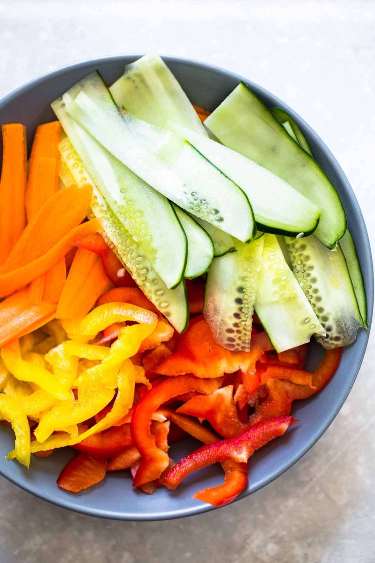 Cucumbers, peppers, and carrots in a bowl.