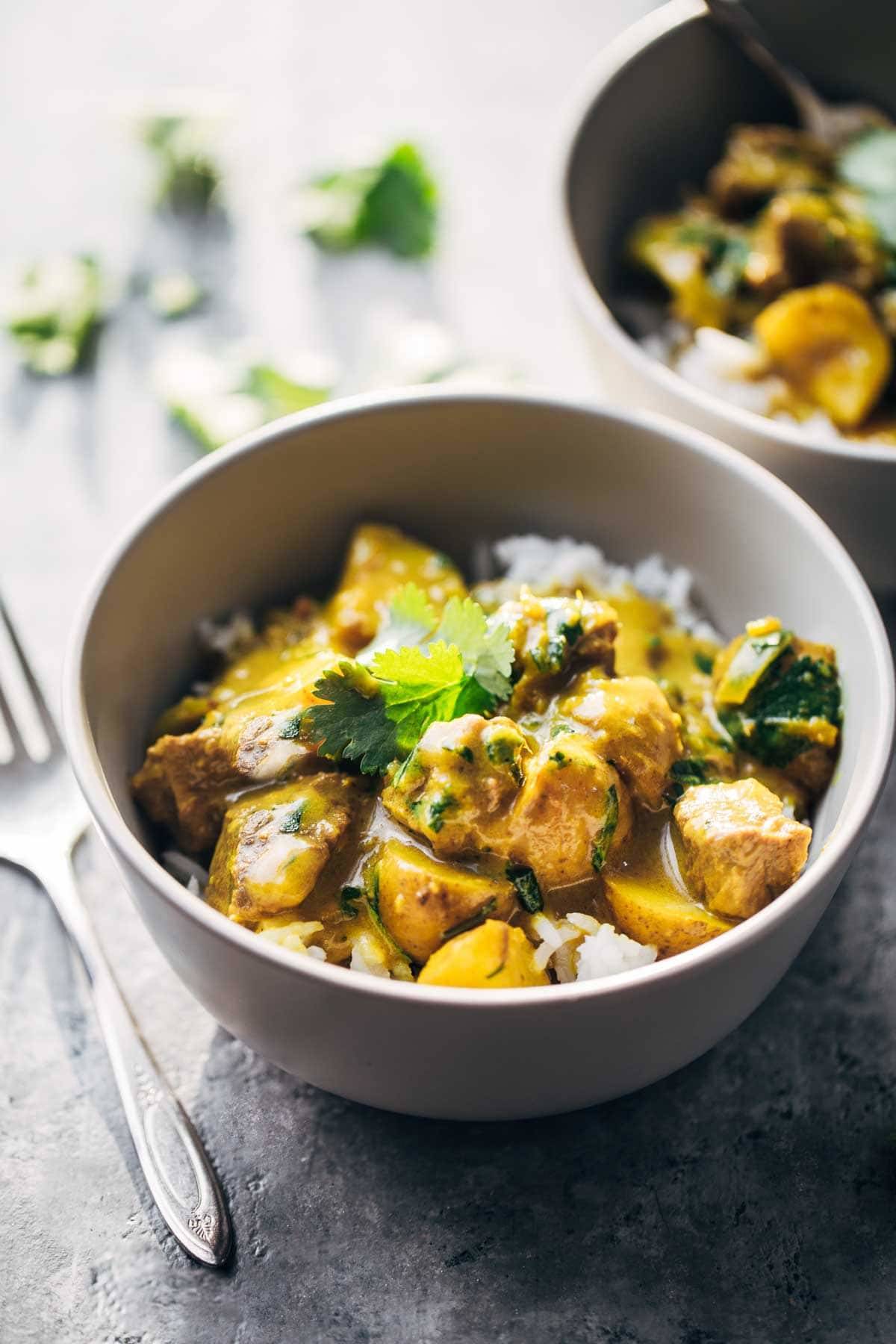 Thai Yellow Curry with Beef and Potatoes in a white bowl with a fork.