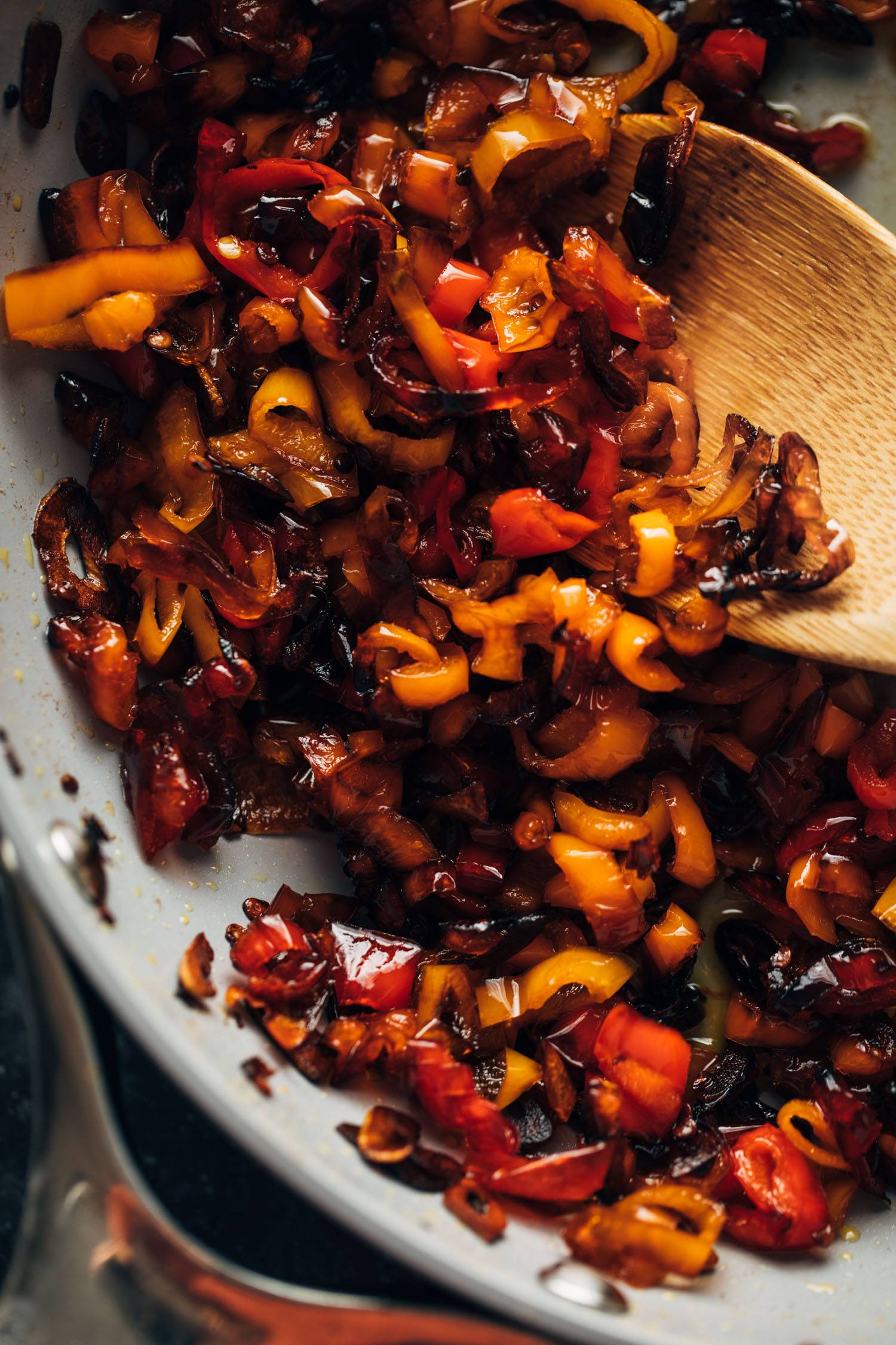 Candied peppers in a pan with a wooden spoon