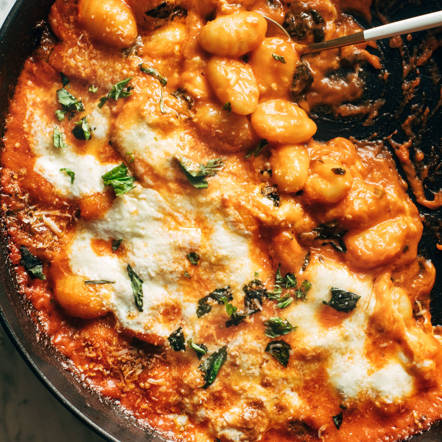 Gnocchi in a cast iron skillet baked under cheese.