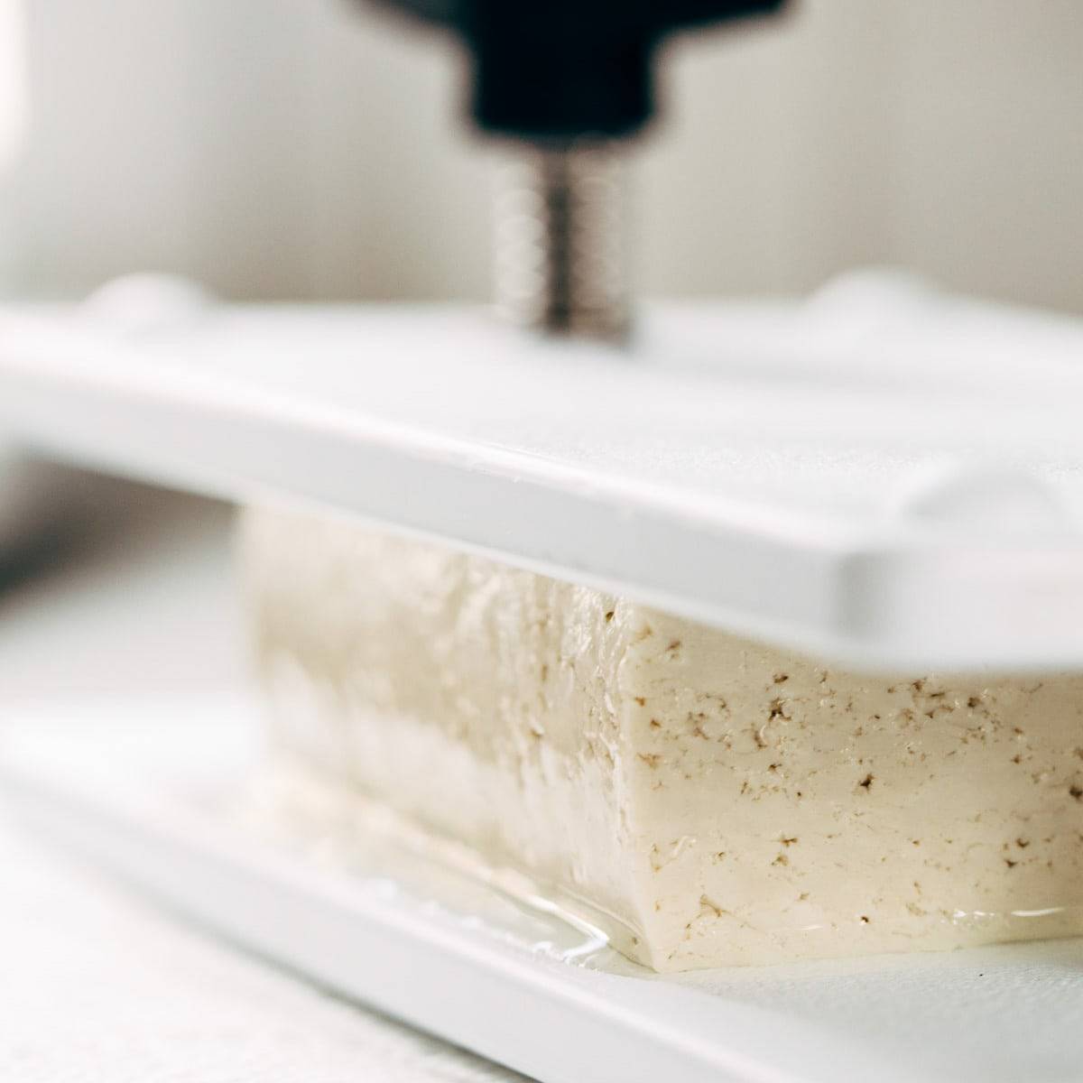 Pressing tofu with a tofu press.