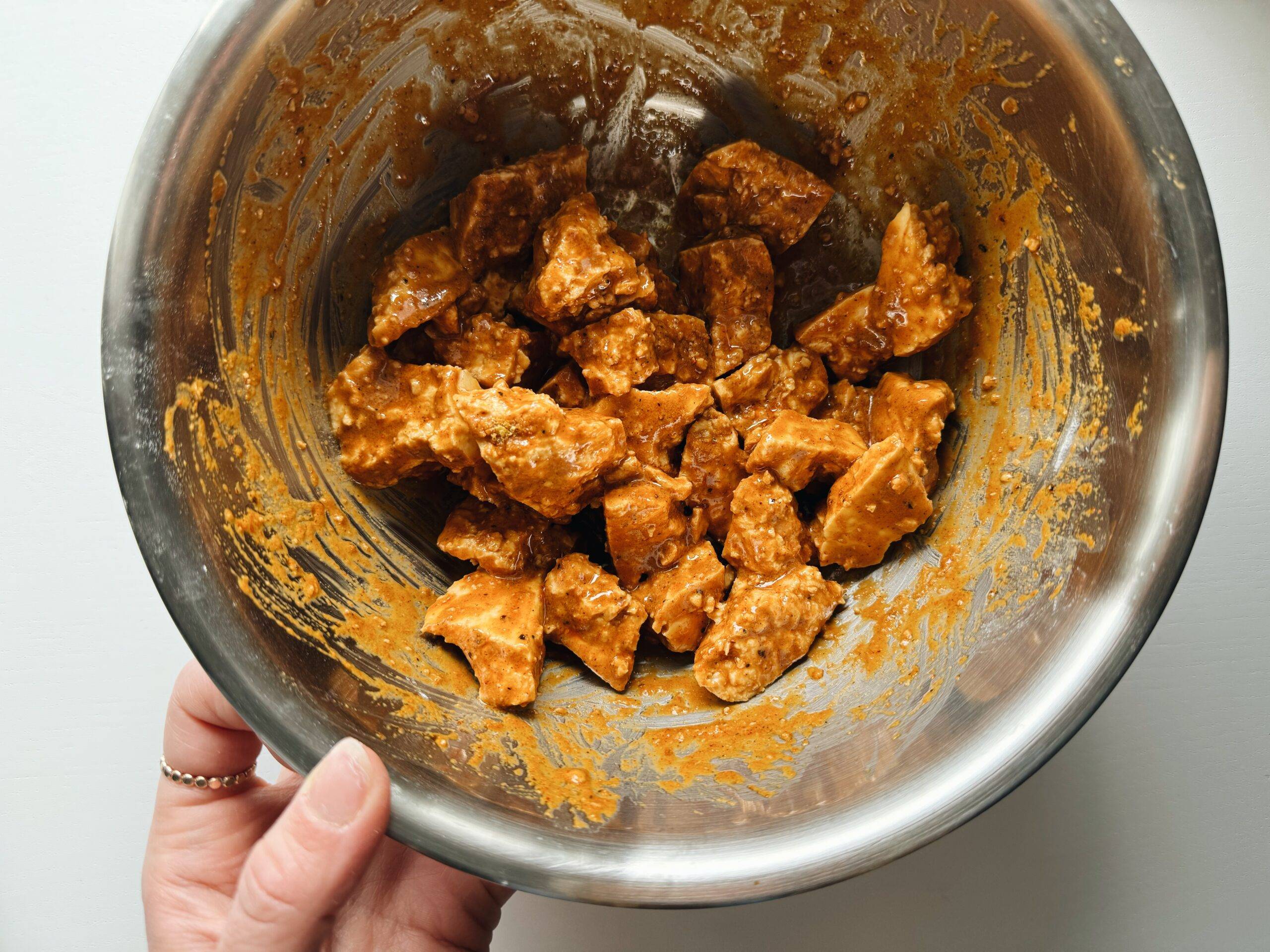 Tossing tofu in batter in a bowl.