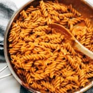 Rotini noodles with vegan vodka sauce in a pan with a wooden spoon.