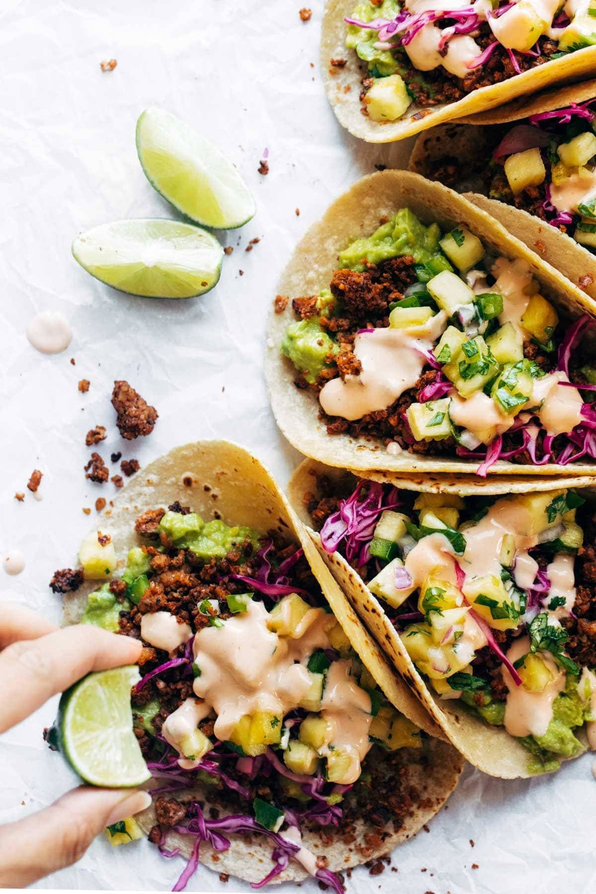 A hand squeezes lime into tacos.