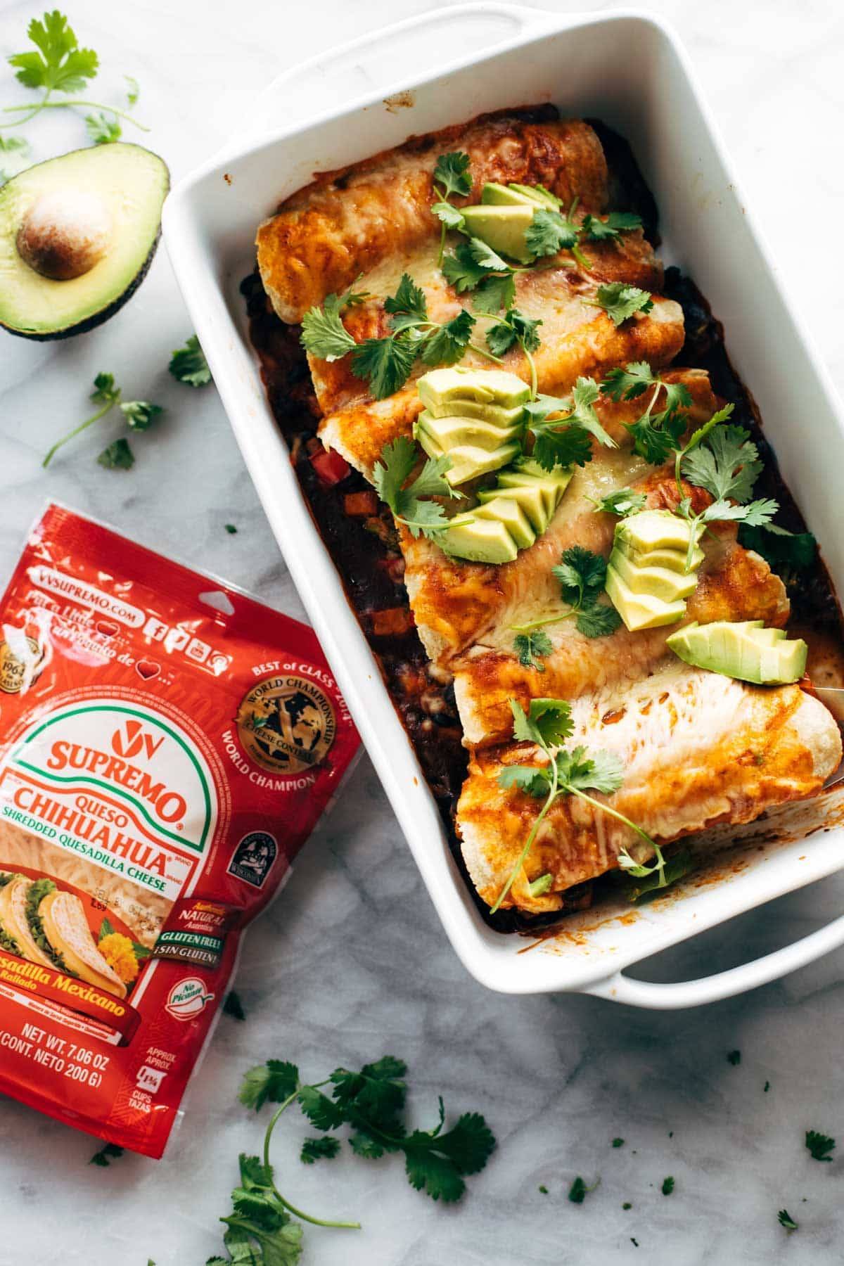 Veggie enchiladas in a pan with Chihuahua Cheese.