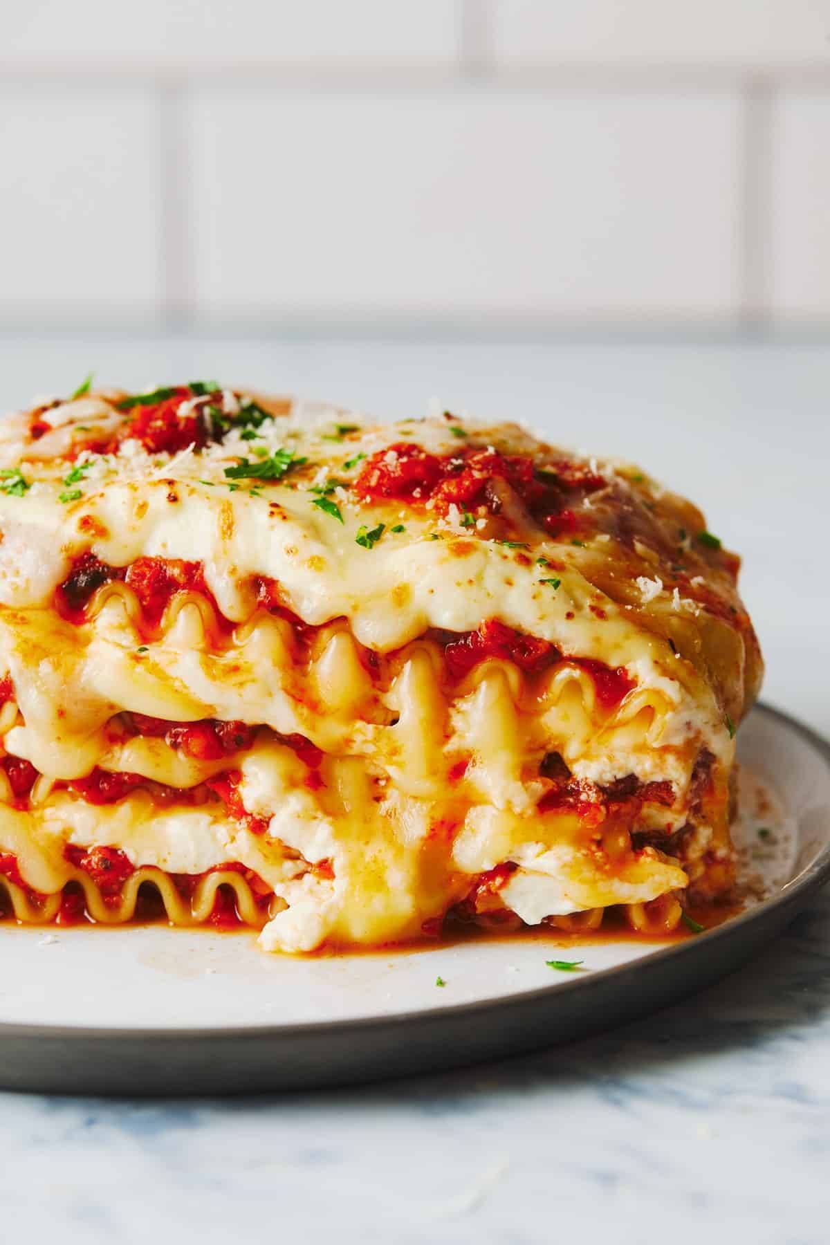 Lasagna oozing cheese on a plate.