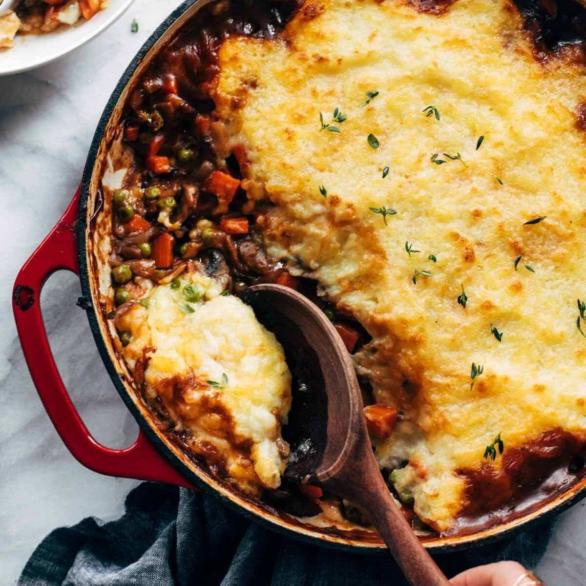 Meatless shepherd's pie being spooned out of a red pot.