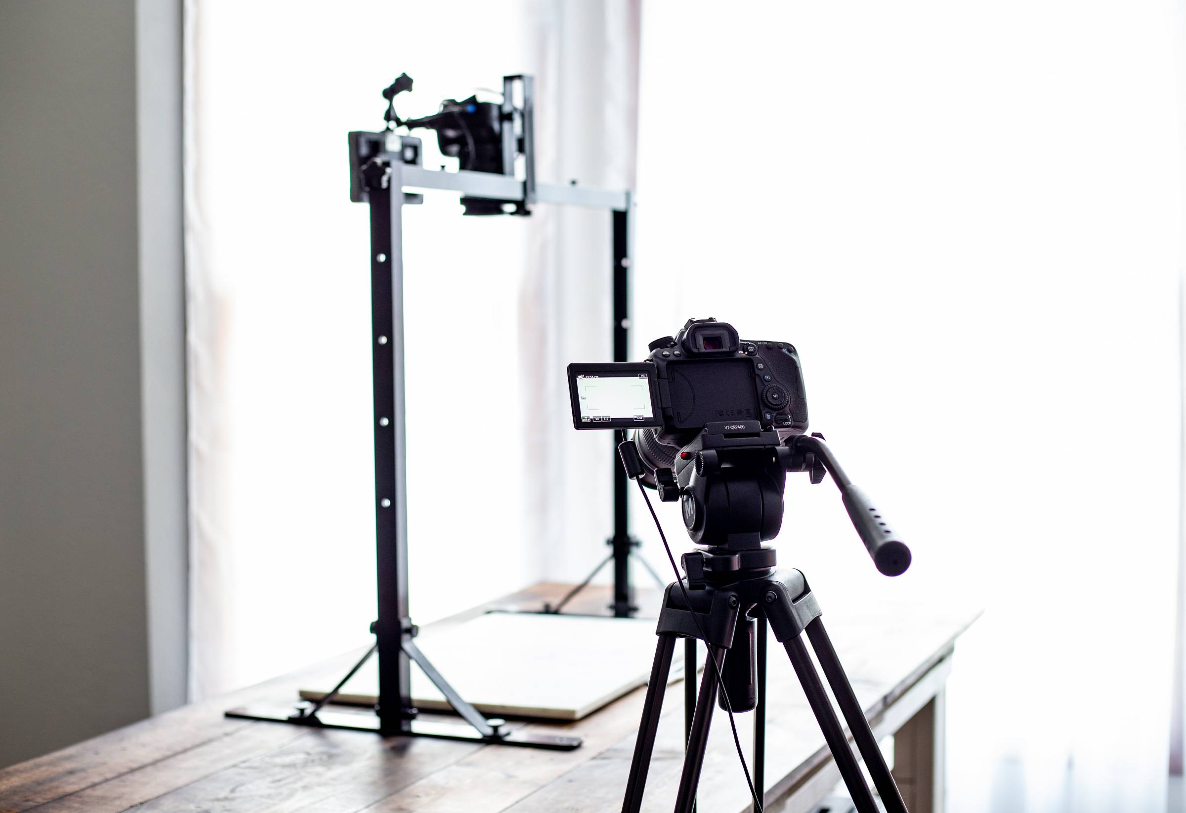 DSLR camera on a tripod and a DSLR camera in the distance on an overhead stand.