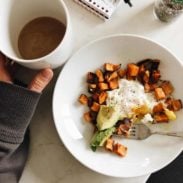 Roasted sweet potatoes, remnants of an avocado, and a fried egg with a side of coffee.