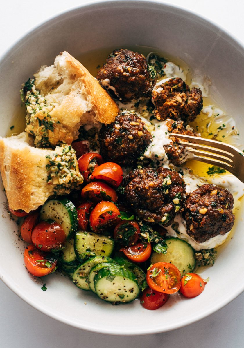 Meatballs in a bowl with a tomato salad and bread