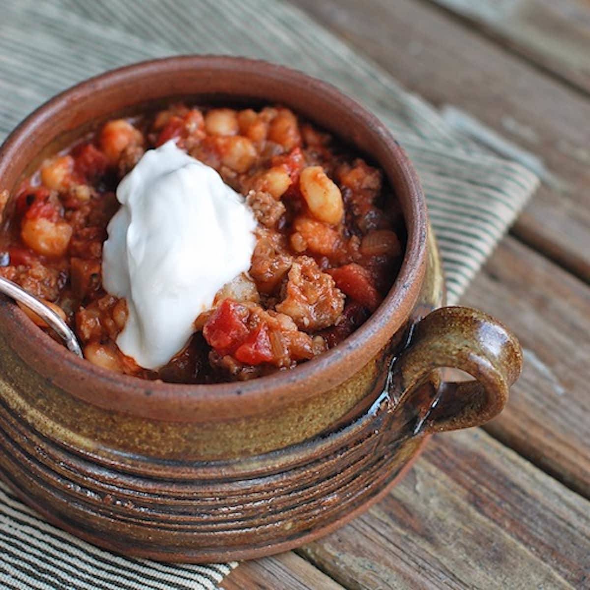 White bean chili with pork in a bowl with sour cream.