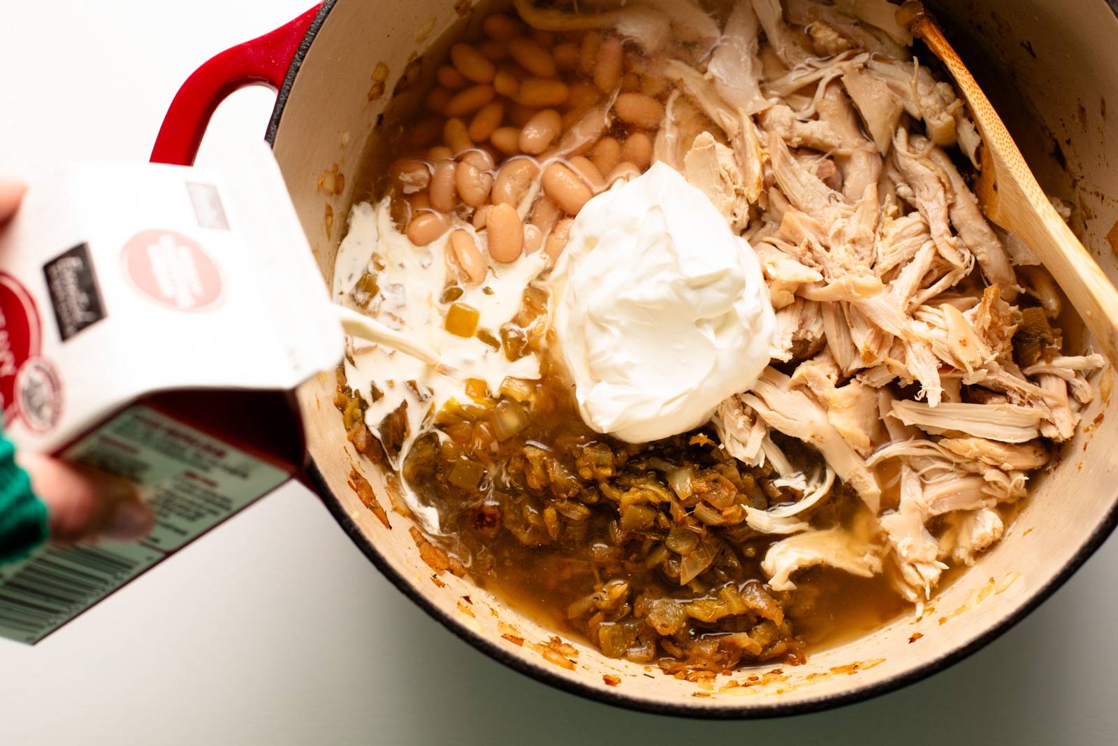 Chicken, sour cream, and beans going into the white chicken chili