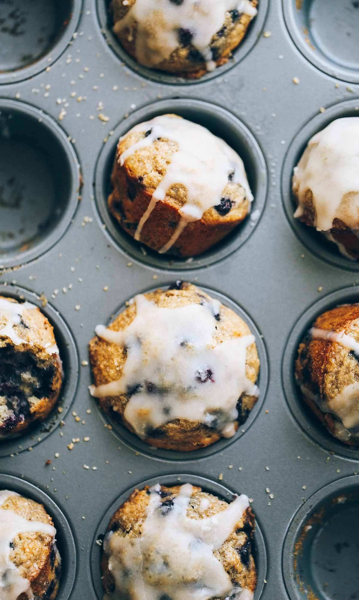 Whole Wheat Blueberry Muffins with glaze in a muffin tin.