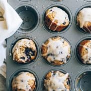 Whole Wheat Blueberry Muffins in a muffin tin with glaze.