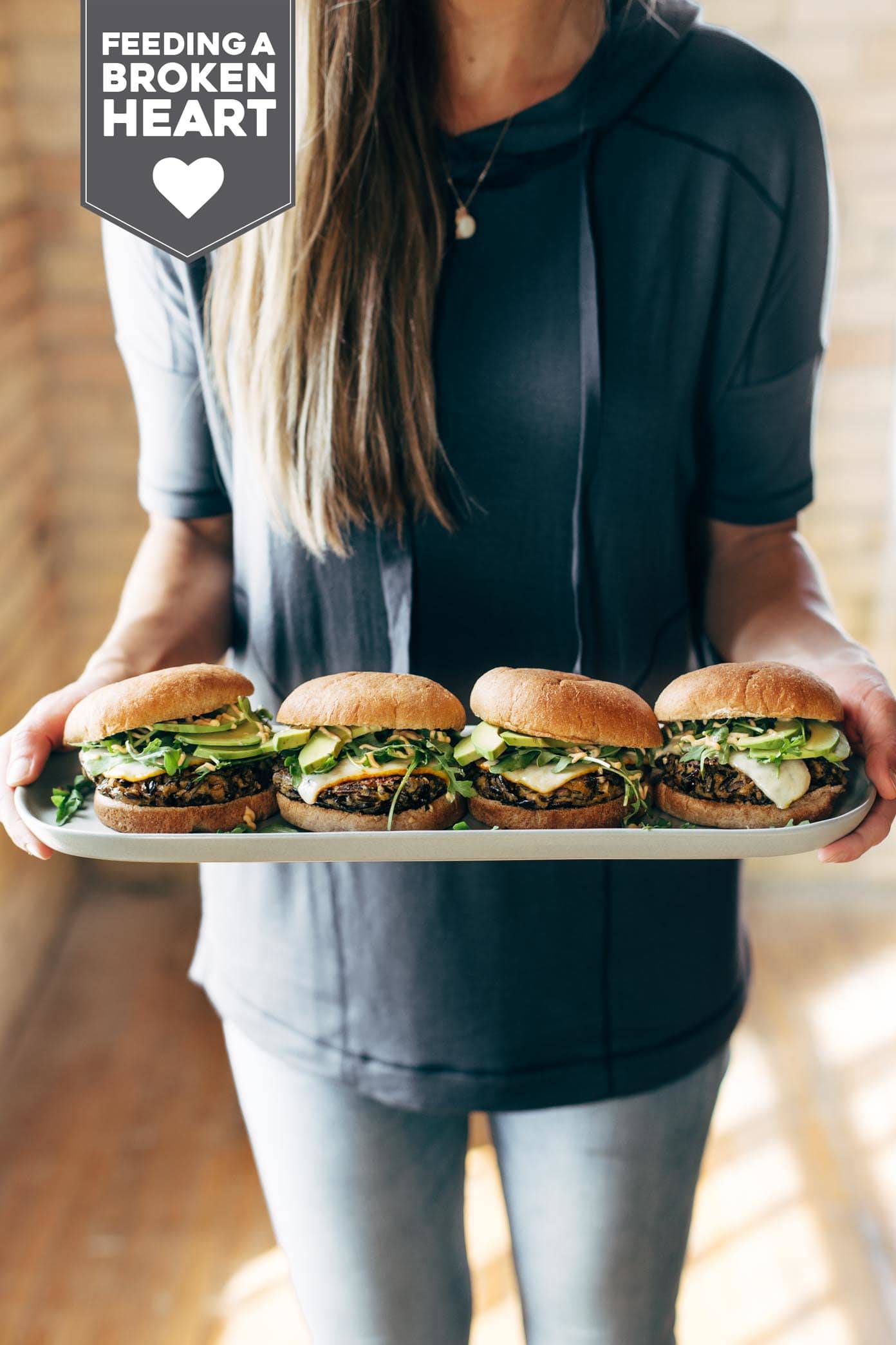 Woman Holding a Plate of Four Wild Rice Burgers.