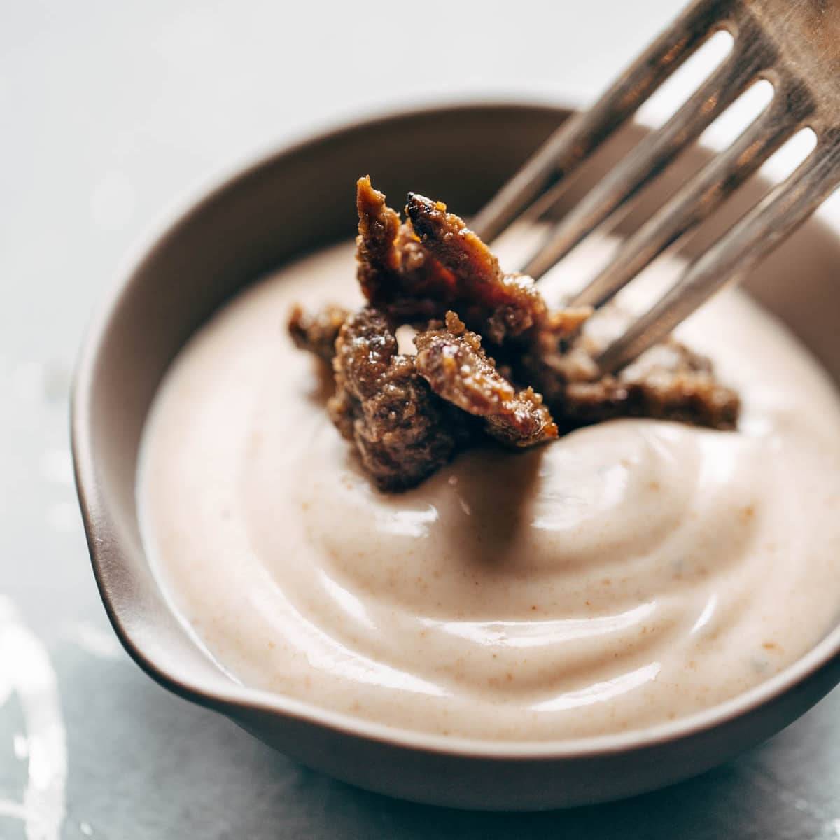 Steak being dipped into a bowl of yum yum sauce with a fork. 