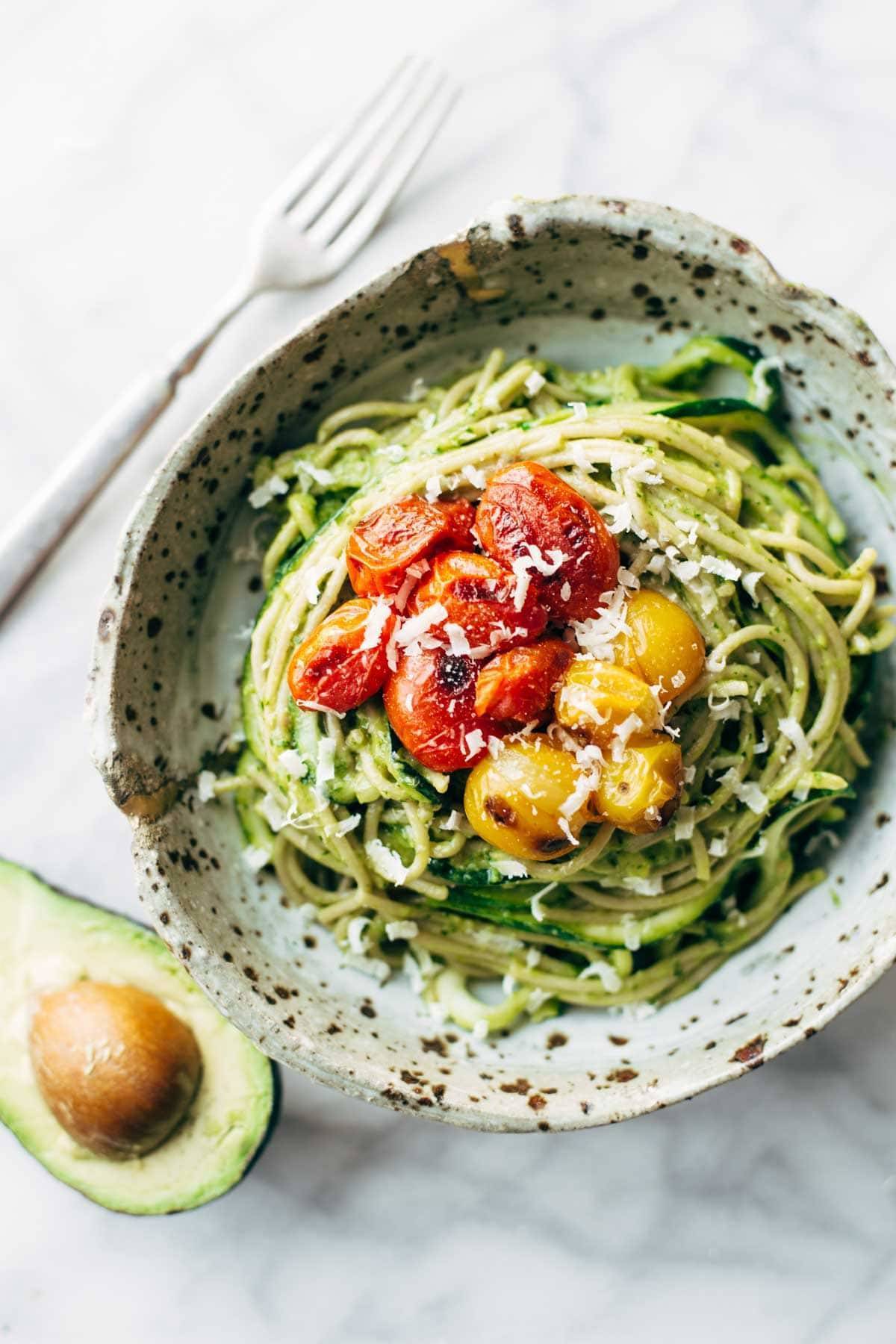 Burst Tomato and Zucchini Spaghetti in a speckled bowl with a fork.