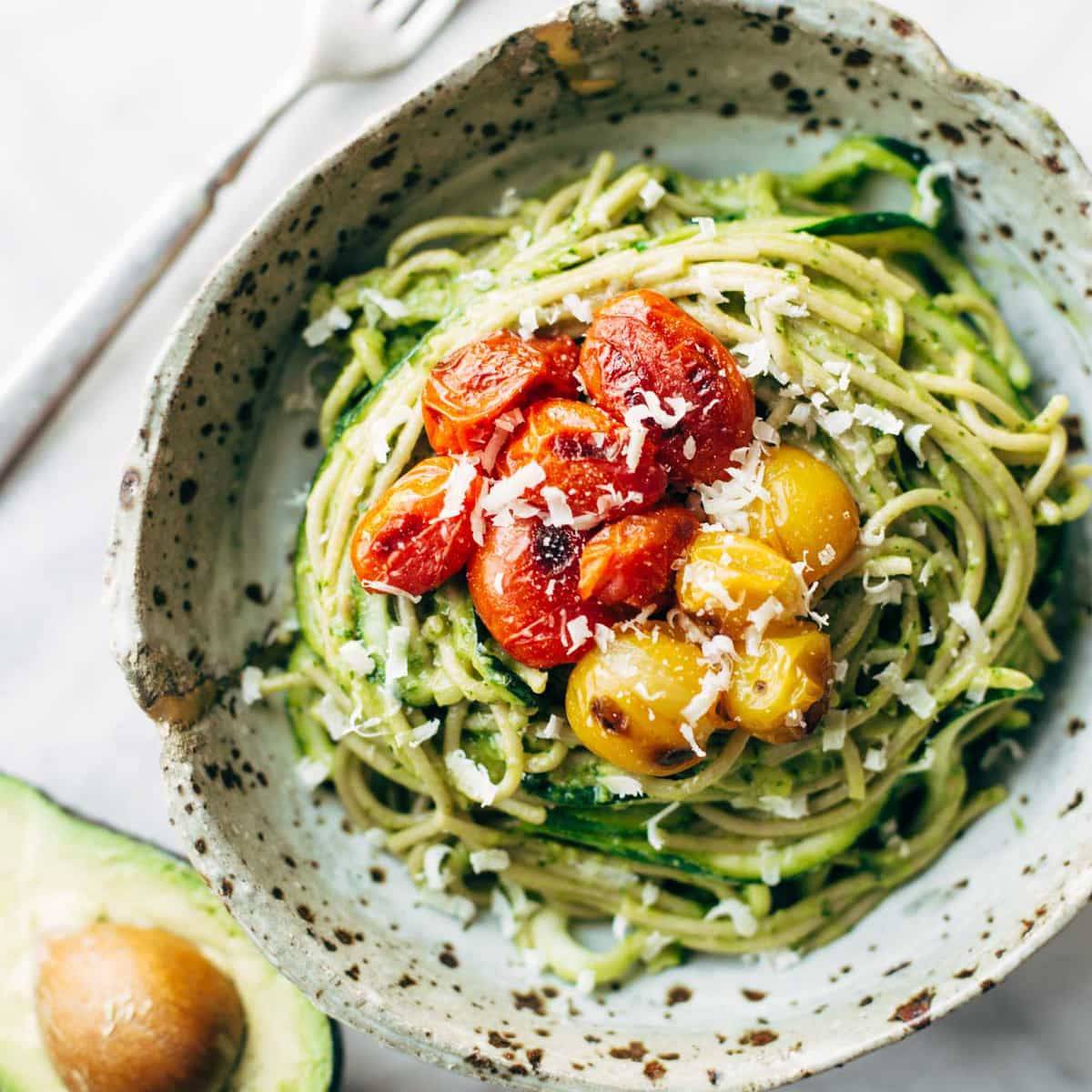 Zucchini Spaghetti with Avocado Sauce in a bowl with tomatoes.