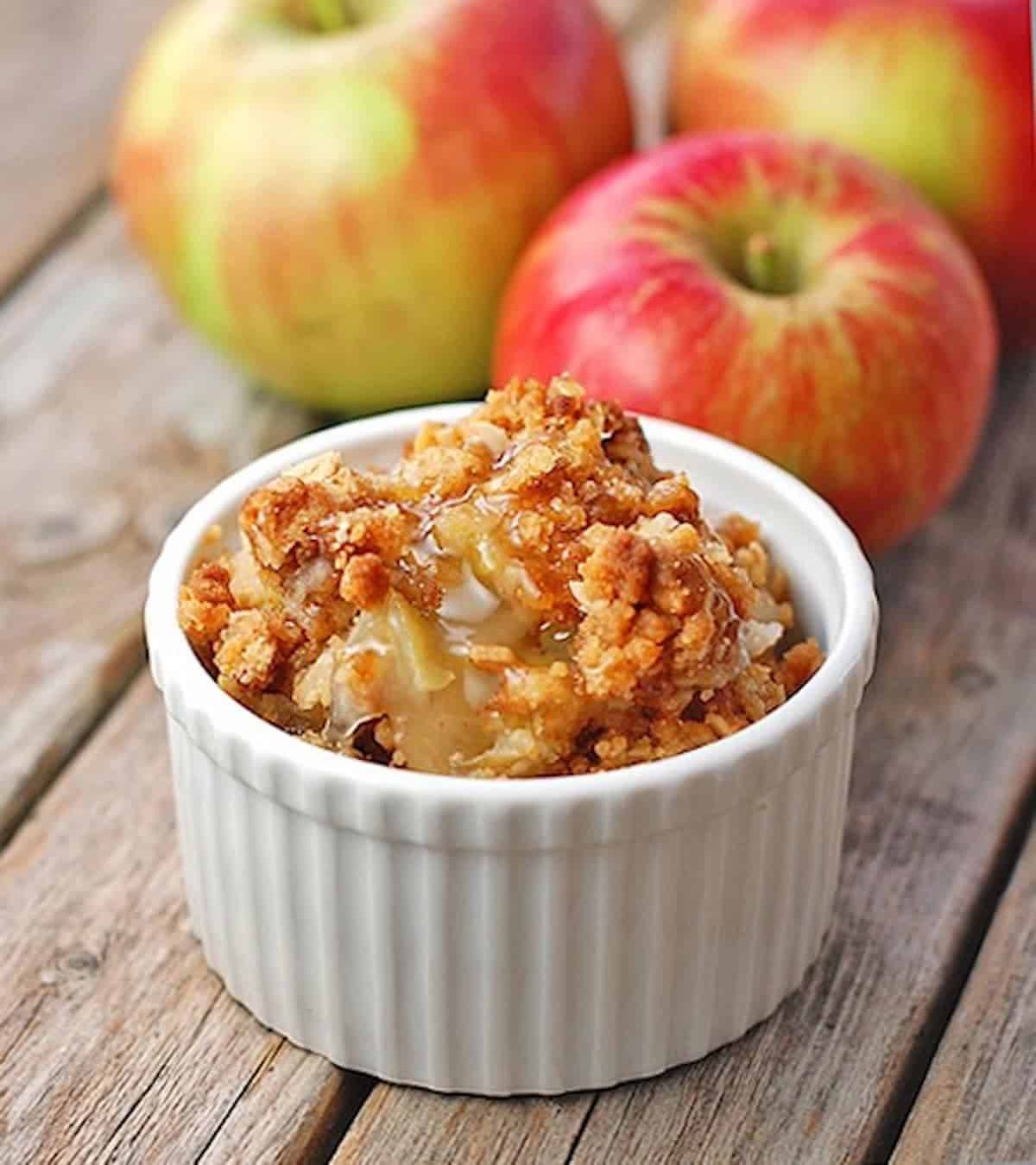 Apple crisp in a white dish with apples.