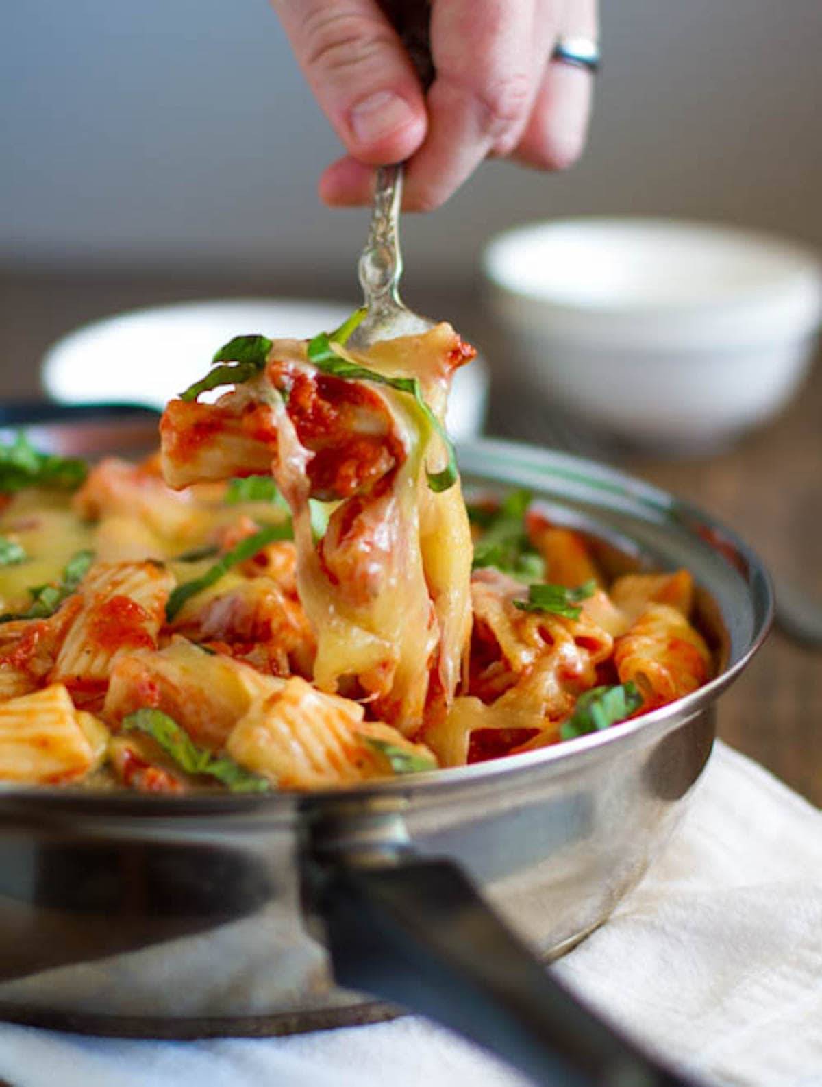 Baked caprese rigatoni in a pan and on a fork.