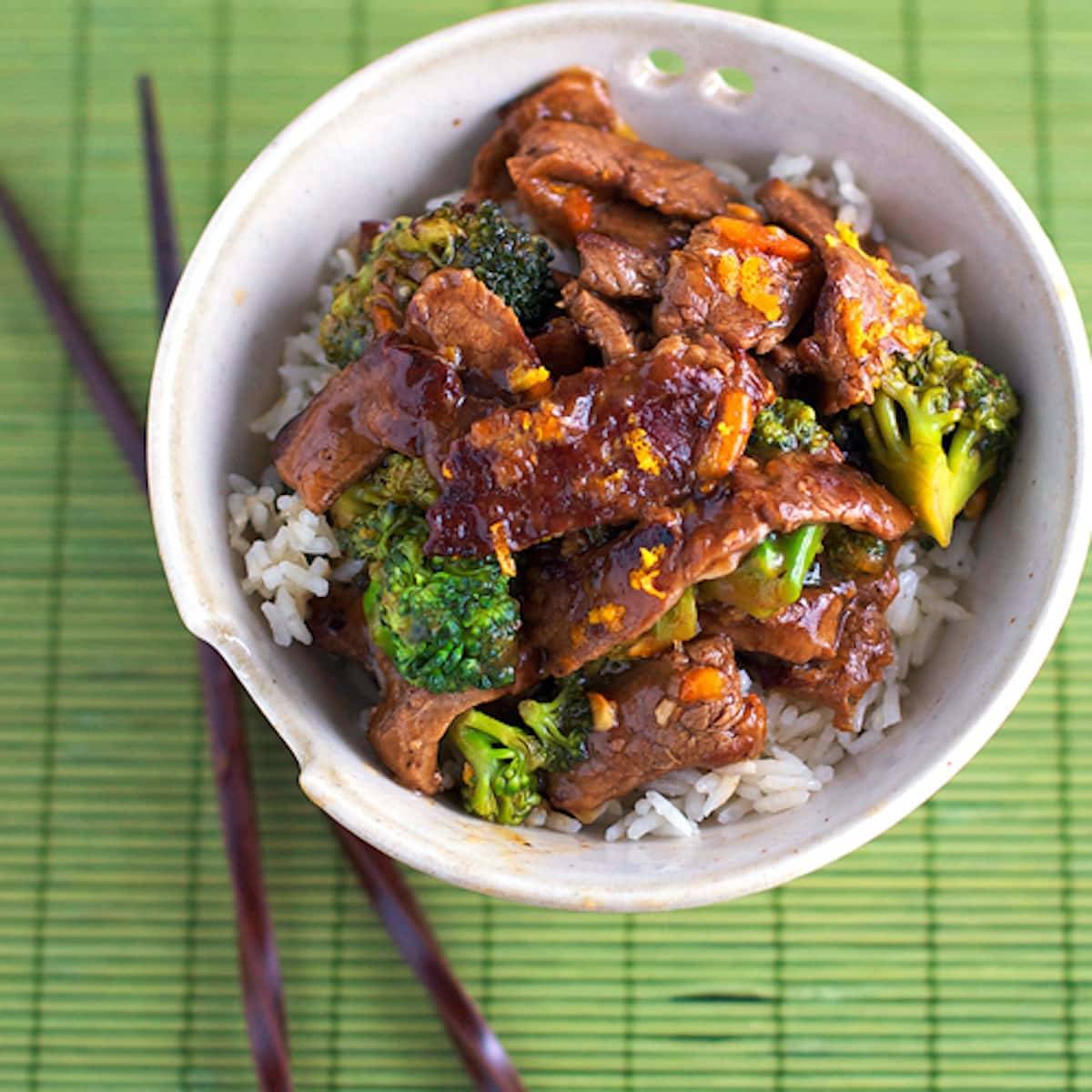 Light orange beef and broccoli in a bowl with rice.