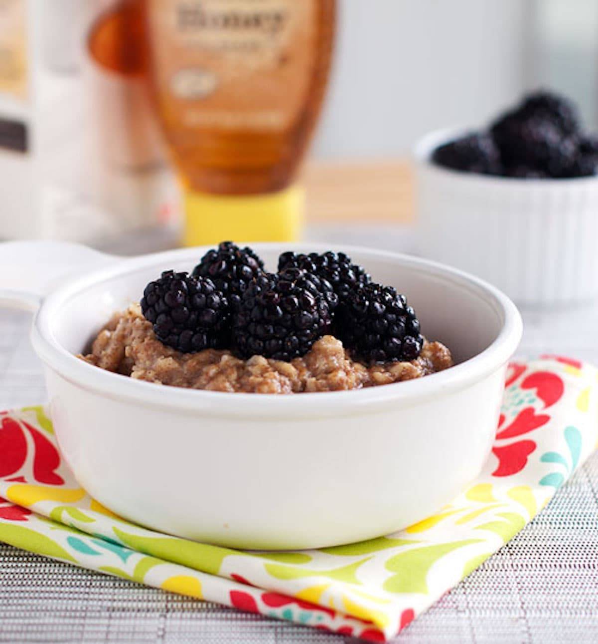 Blackberries and cream oats in a white dish on a colorful napkin.