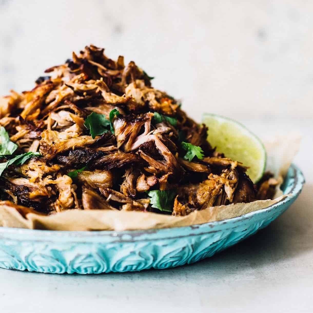 Crockpot carnitas in a bowl with lime.