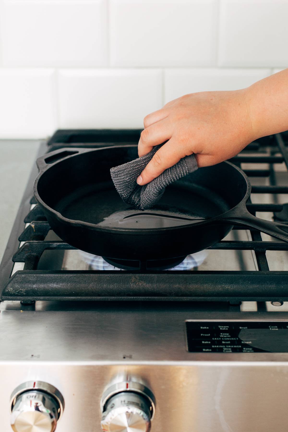 Person rubbing oil into Pan made of cast iron with a cloth.