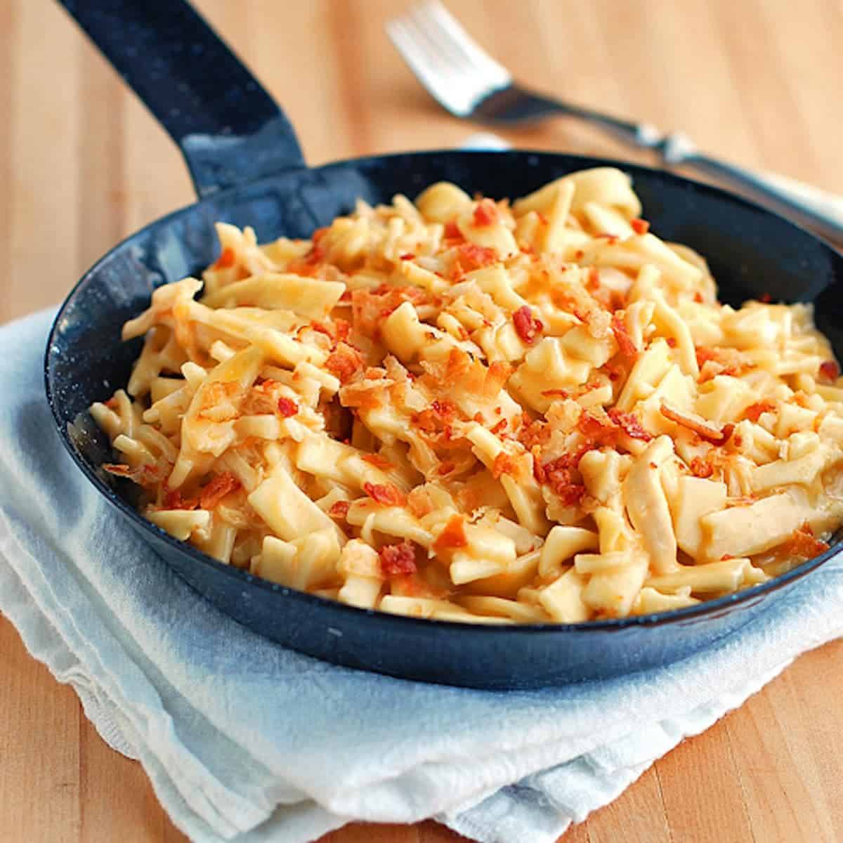 Cheesy chicken noodles coated in a creamy sauce and tossed with shredded chicken in a skillet.