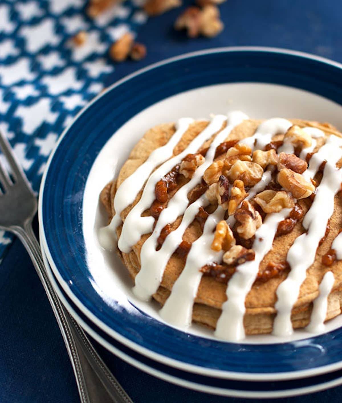 Cinnamon roll pancakes with Greek yogurt frosting in a blue and white bowl.
