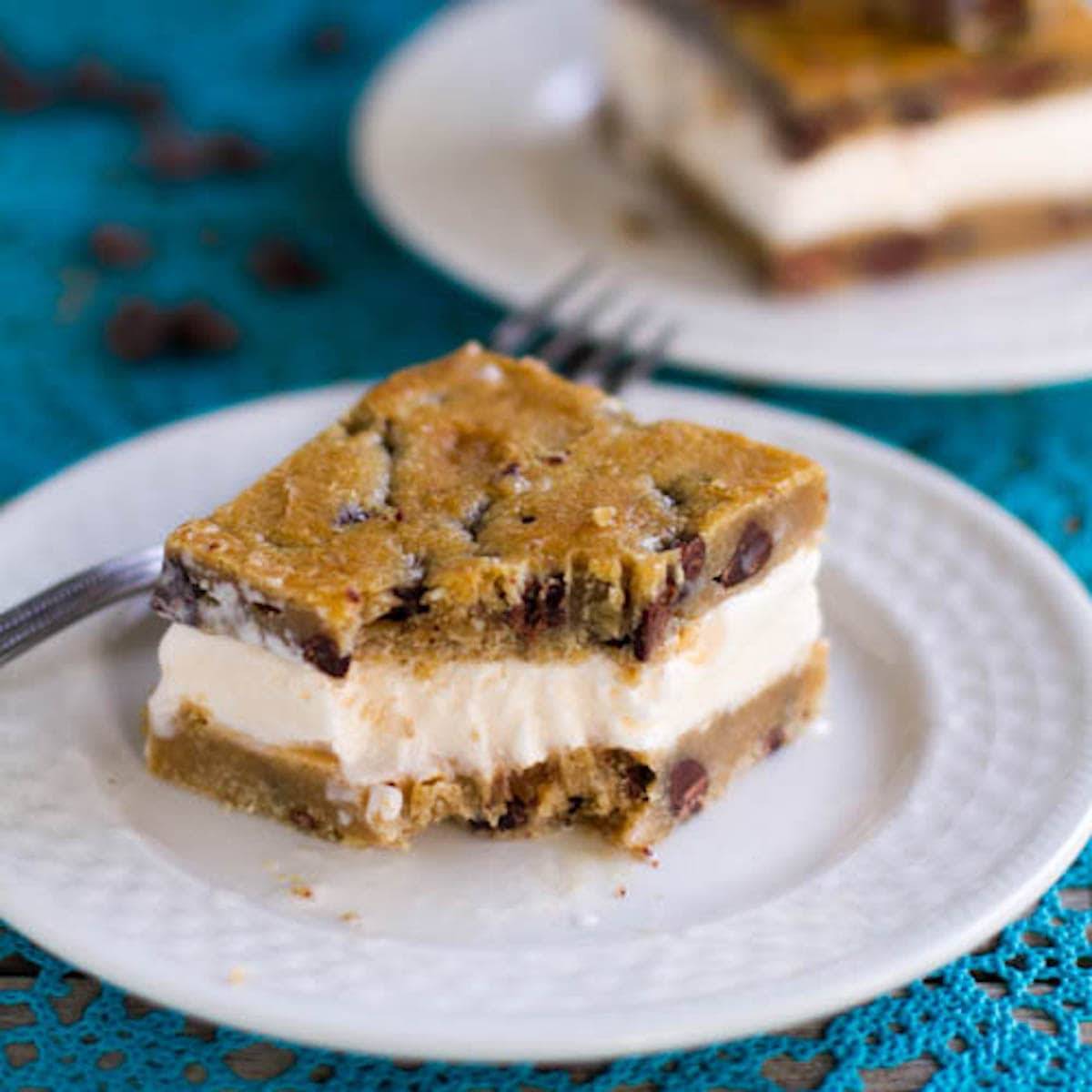 Chocolate chip cookie ice cream bar on a plate with a piece removed.