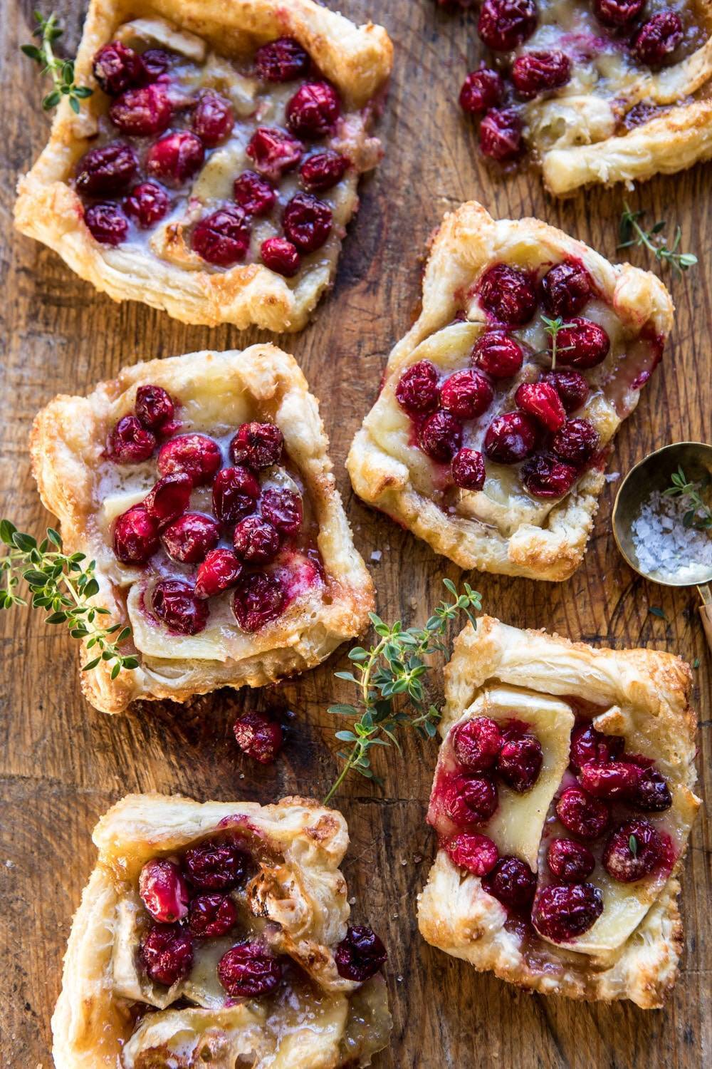 Cranberry Brie Pastry Tarts on a wood table with fresh thyme.